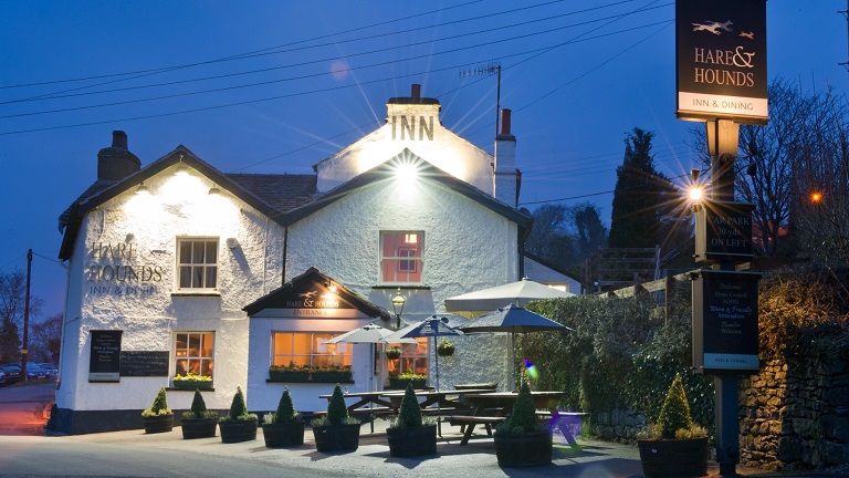 The outside of the dog-friendly Hare & Hounds pub at night lit up by spotlights